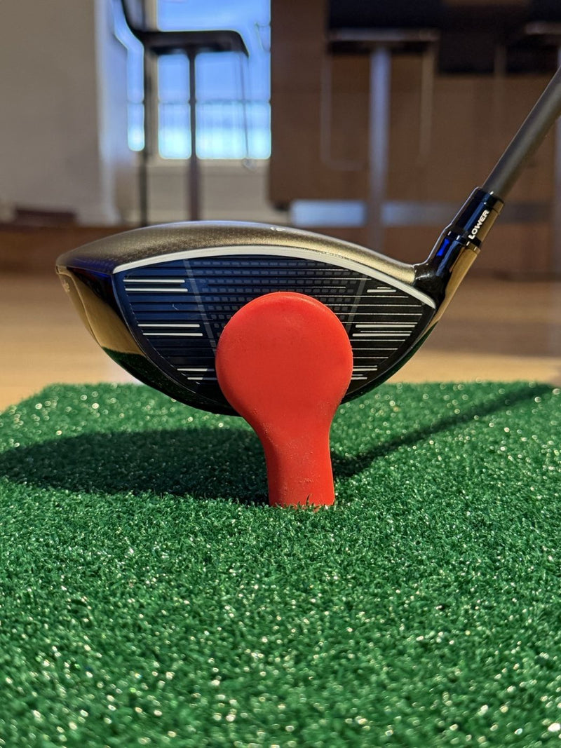 Driver head set up behind the red strike target on the mat